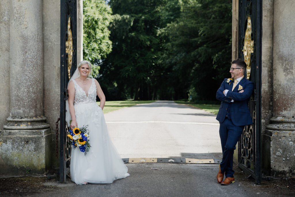 Wedding Photography: bride and groom stand inside a large gate to a grand house